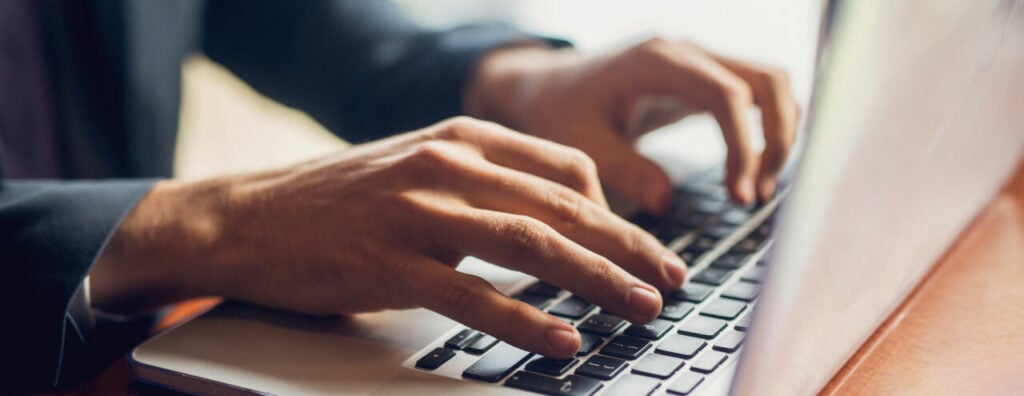 Person typing on a computer researching a software for reconciliation
